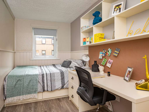 A bedroom with a bed, desk, and chair.
