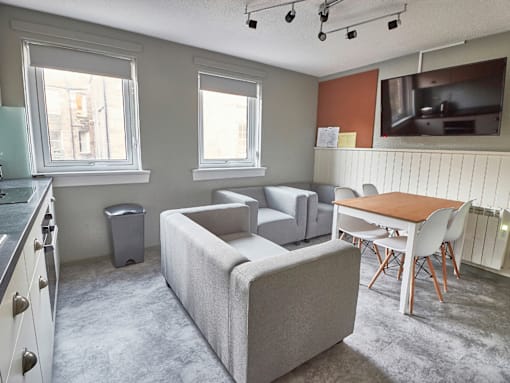 A grey couch sits in a living room with a television in the corner.