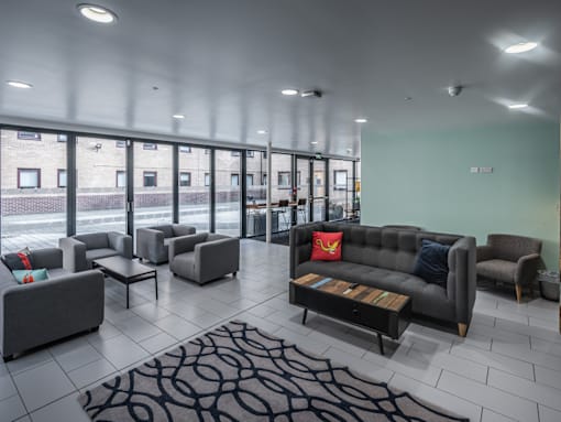 A spacious waiting room with grey couches and a patterned rug.