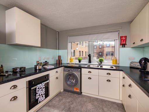 A kitchen with a washing machine built into the cabinetry.