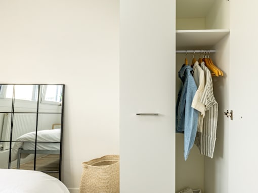A white closet with clothes hanging on a hanger.