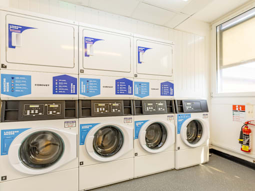 A row of washing machines with instructions on the wall.