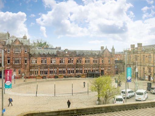 A large building with a lot of windows and a courtyard in front.
