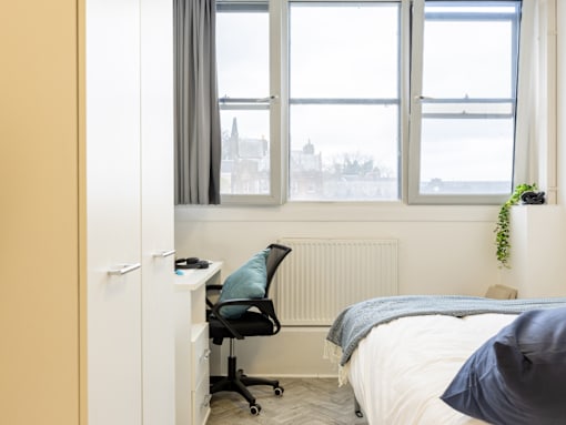 A bedroom with a bed, desk, and chair.