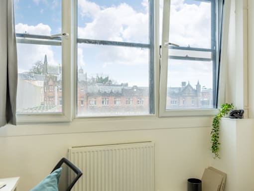 A window with a view of a town and a radiator on the wall.