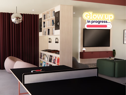 A ping pong table is in the middle of a room with a neon sign that says "Glow up in progress...".