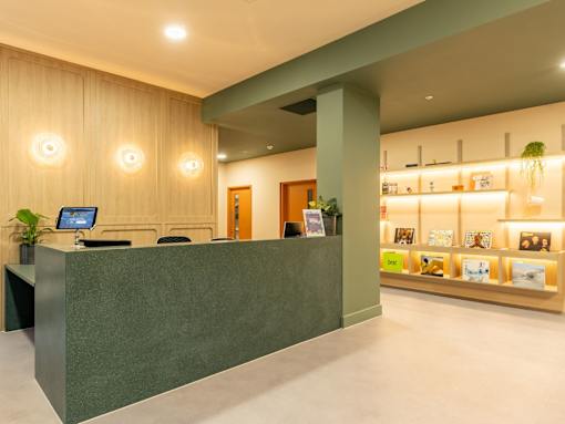 A reception area with a green desk and a wall of books.