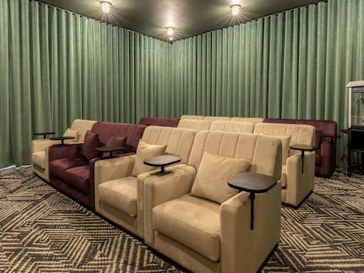 A row of beige and burgundy couches are lined up in a room with green curtains.