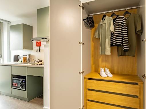 A small closet with a striped shirt hanging on it.