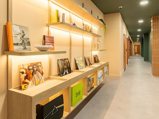 A hallway with a long row of shelves with books and pictures on them.