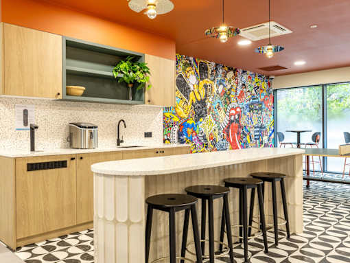 A kitchen with a bar and stools in front of a mural.