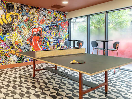 A ping pong table is in the middle of a room with a black and white checkered floor.