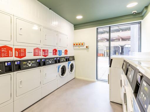 A row of washing machines are lined up in a laundromat.