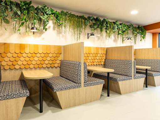 A row of wooden chairs with grey patterned cushions are arranged in a row.