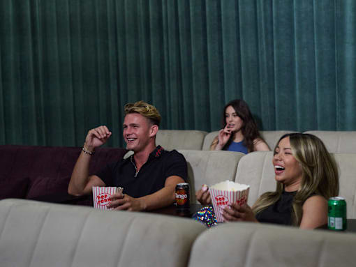 A group of people are sitting in a movie theater watching a movie on a large screen.