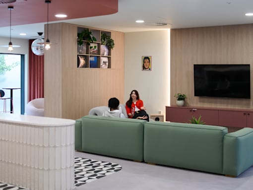 Two people sitting on a green couch in a living room.