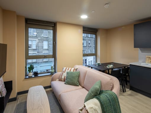 A living room with a couch, a table, and a window with a view of a building.