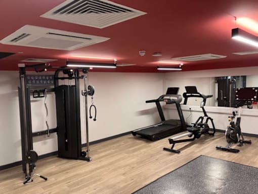 A gym with a variety of equipment including treadmills, stationary bikes, and weight machines.