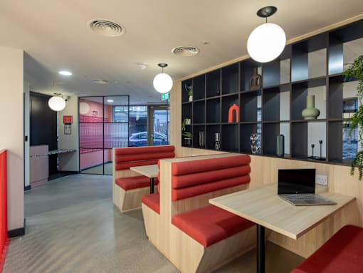 A modern cafe with red booths and wooden tables.