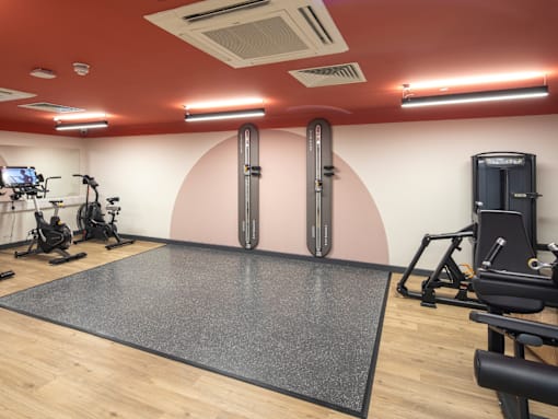 A gym with a variety of equipment including treadmills, stationary bikes, and weight machines.