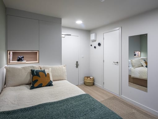 A bedroom with a bed, a mirror, and a painting on the wall.