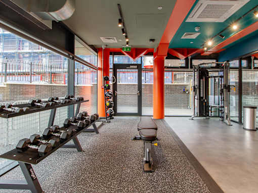 A different angle of the on-site gym with a bench and dumbells