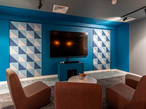 Cinema room television and seating nearby. The TV is wall-mounted against a blue patterned wall.