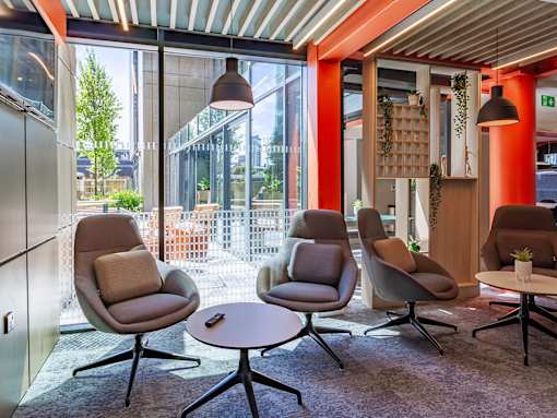 Chill-out area with comfortable chairs with pillows and a small round table. Nearby to a large window looking out onto the courtyard.