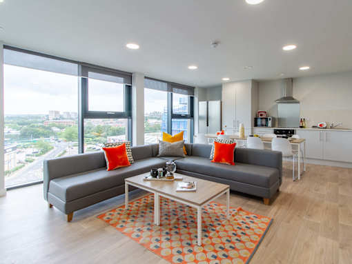 Shared flat sofa and coffee table, with large windows with a view of greenery outside.