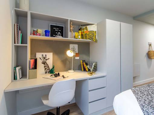 White desk in the bedroom, with plenty of shelving, drawers and a chair.