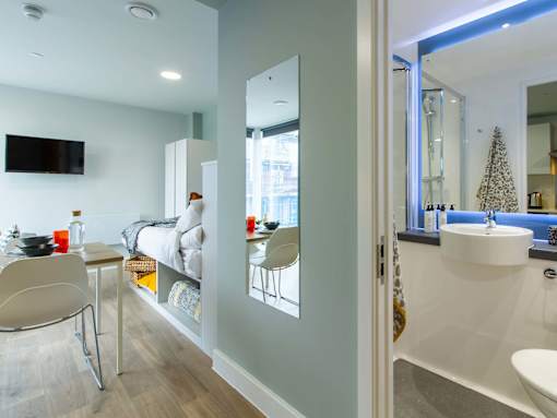 Image of bedroom from the bathroom, showing the large bathroom mirror, a wall-mounted mirror and bed.