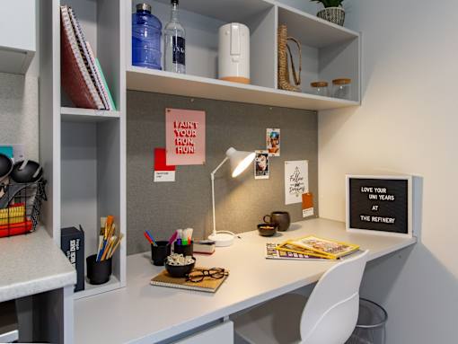 Close up of white desk, with a small lamp and a chair.