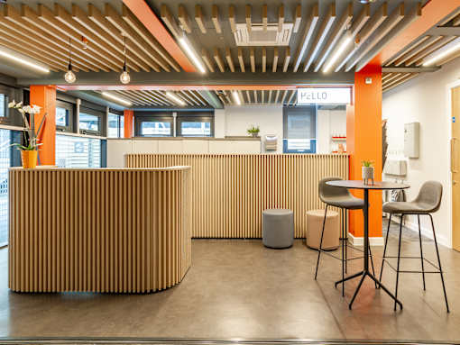 Bright reception space with brown panelling, stools and a high table.