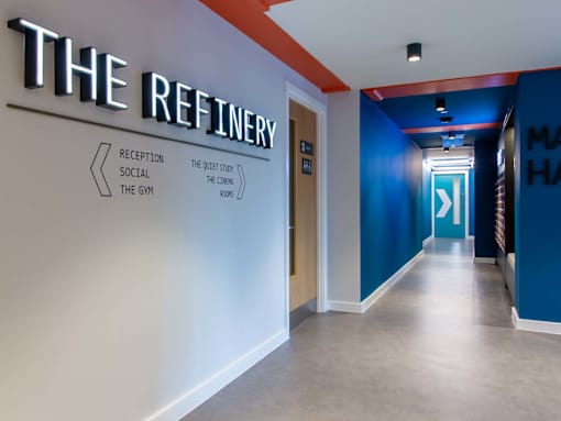 Corridor signage, pointing to the different social spaces and the site name 'The Refinery'