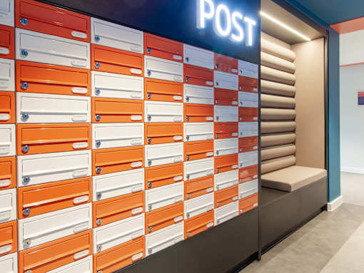 Orange and yellow metal post boxes in a wall.