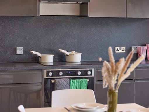 A modern kitchen with a black countertop and a white dining table set for two.
