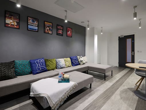 A room with a grey couch and a table with a white cloth on it.