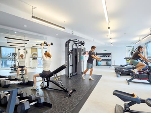 A gym with people exercising and various equipment.
