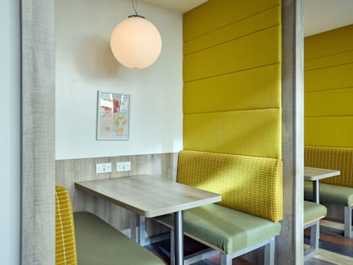 A yellow chair sits next to a table in a room.