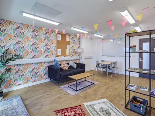 A room with a couch, chairs, and a whiteboard.