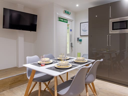 A dining room with a white table and grey chairs.