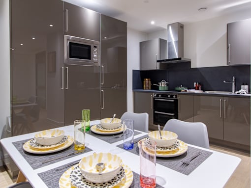 A modern kitchen with a dining table set for two.