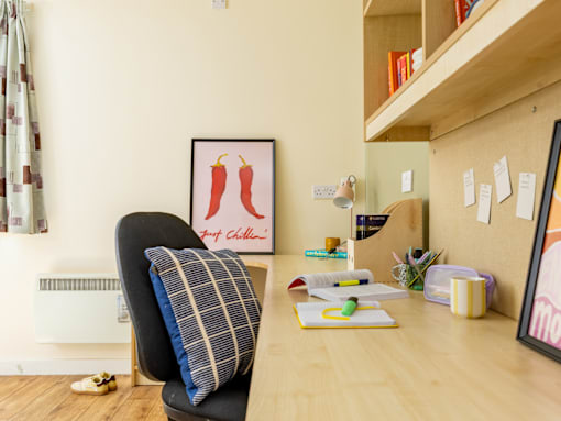 A room with a chair and a table with a picture of two chili peppers on the wall.