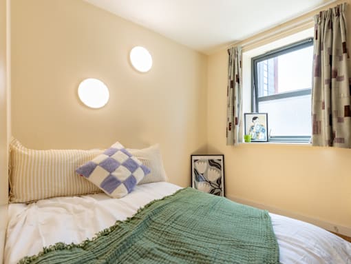 A bed with a green blanket and a blue and white pillow.