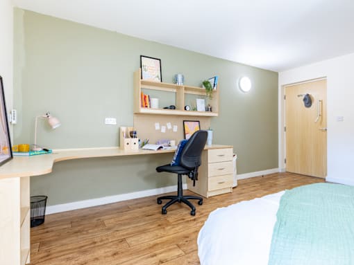 A room with a desk, chair, and bed.