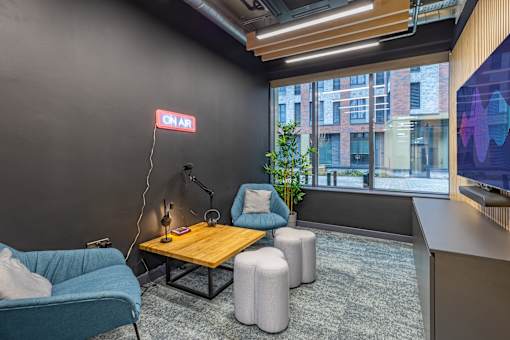 A modern office space with a blue sofa, a wooden table, and a neon sign that reads "ONAR".