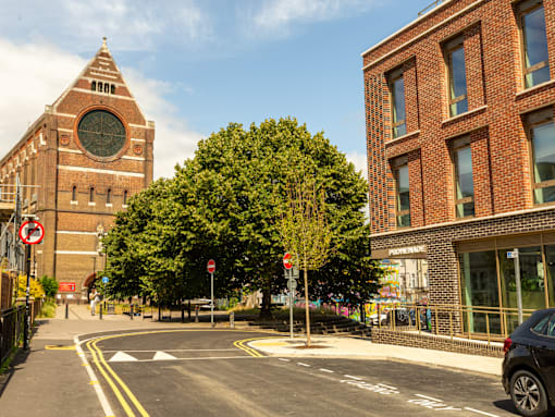 A church with a clock tower is next to a building with a Renoir painting on the wall.