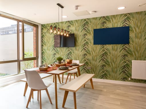 A dining room with a table set for two and a wallpapered green wall.