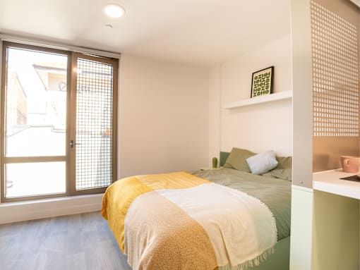 A bedroom with a bed covered in a yellow and white blanket.