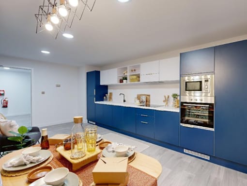 A modern kitchen with blue cabinets and a dining table set for a meal.
